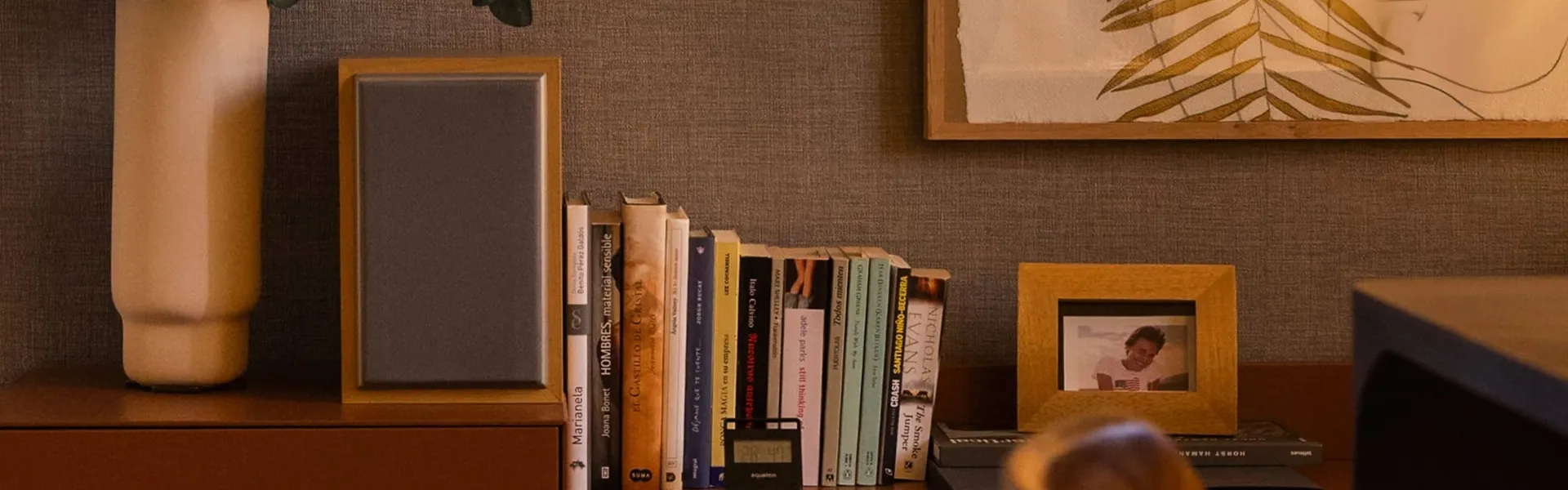 Estantería y mesa auxiliar con libros e iluminación cálida