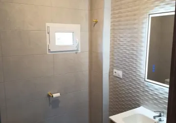 Baño con ducha, revestimiento claro y mueble de lavabo