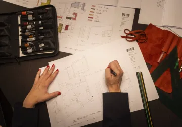Manos trabajando sobre un plano con muestras de materiales