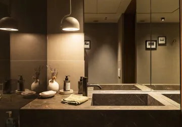 Baño en tonos oscuros con iluminación sobre el lavabo