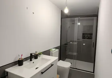 Baño renovado con ducha y lavabo en tonos neutros