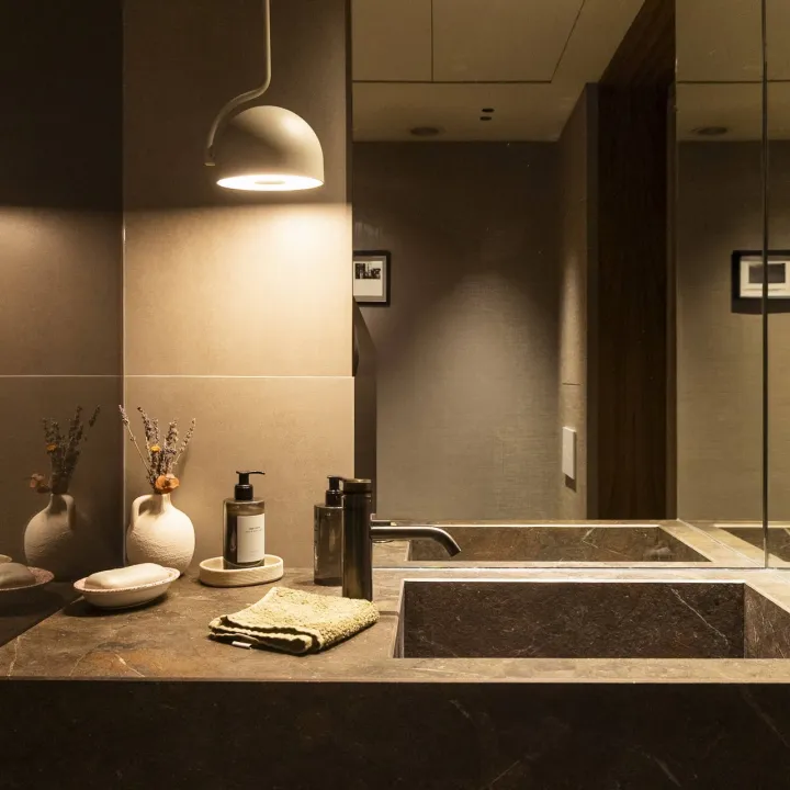 Baño en tonos oscuros con iluminación sobre el lavabo